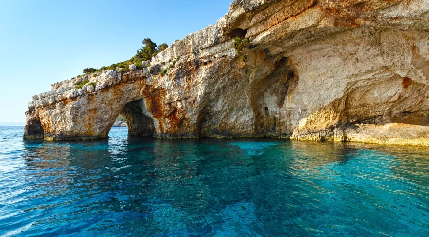 Twin limestone arches of the Blue Caves at Cape Skinari with turquoise water beneath