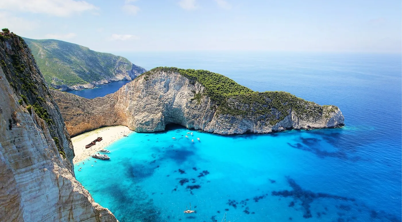 Aerial view of Navagio Shipwreck Beach with white sand and turquoise water below sheer cliffs