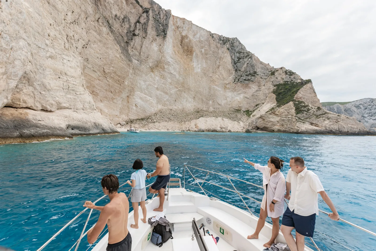 Passengers on the bow pointing at the cliffs as the boat rounds a headland