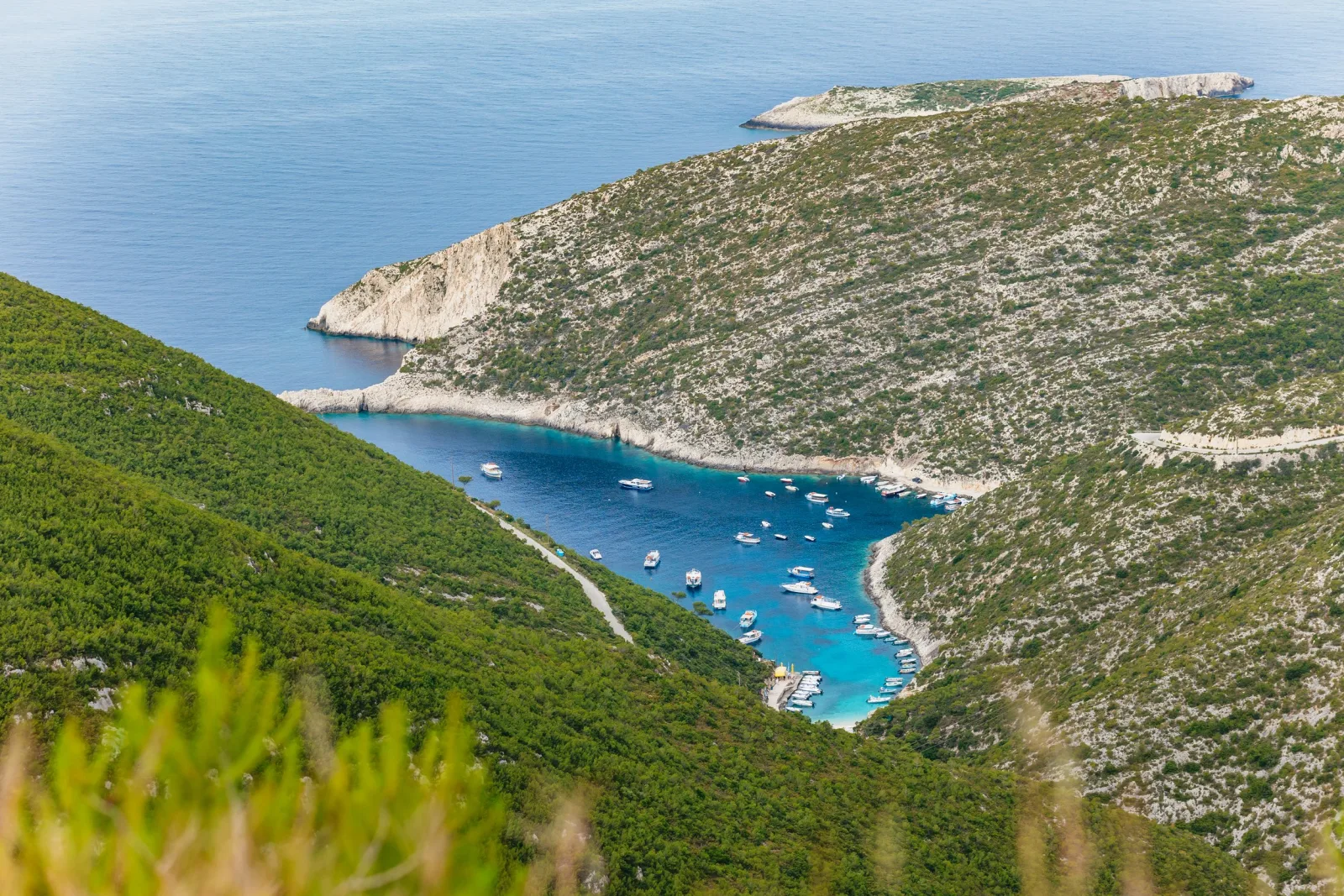 Looking down onto the Porto Vromi harbour cove with boats moored in green water