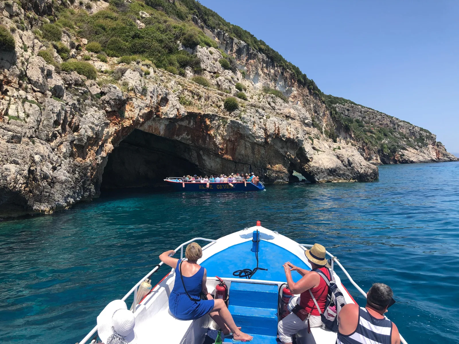 Passengers on the bow approaching a cave mouth that another boat has just entered