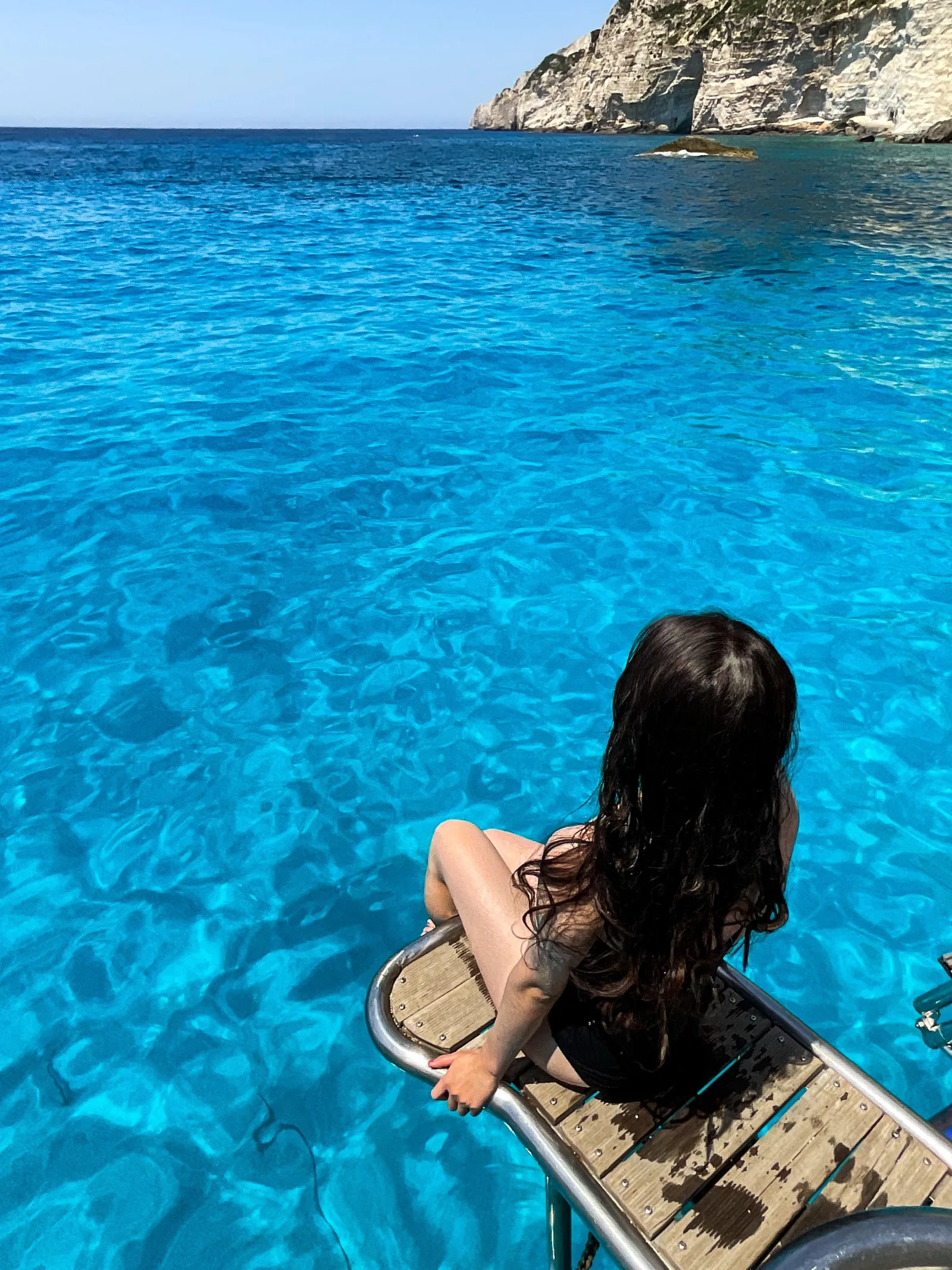 A traveller on the bow of the boat over transparent turquoise water at a swim stop