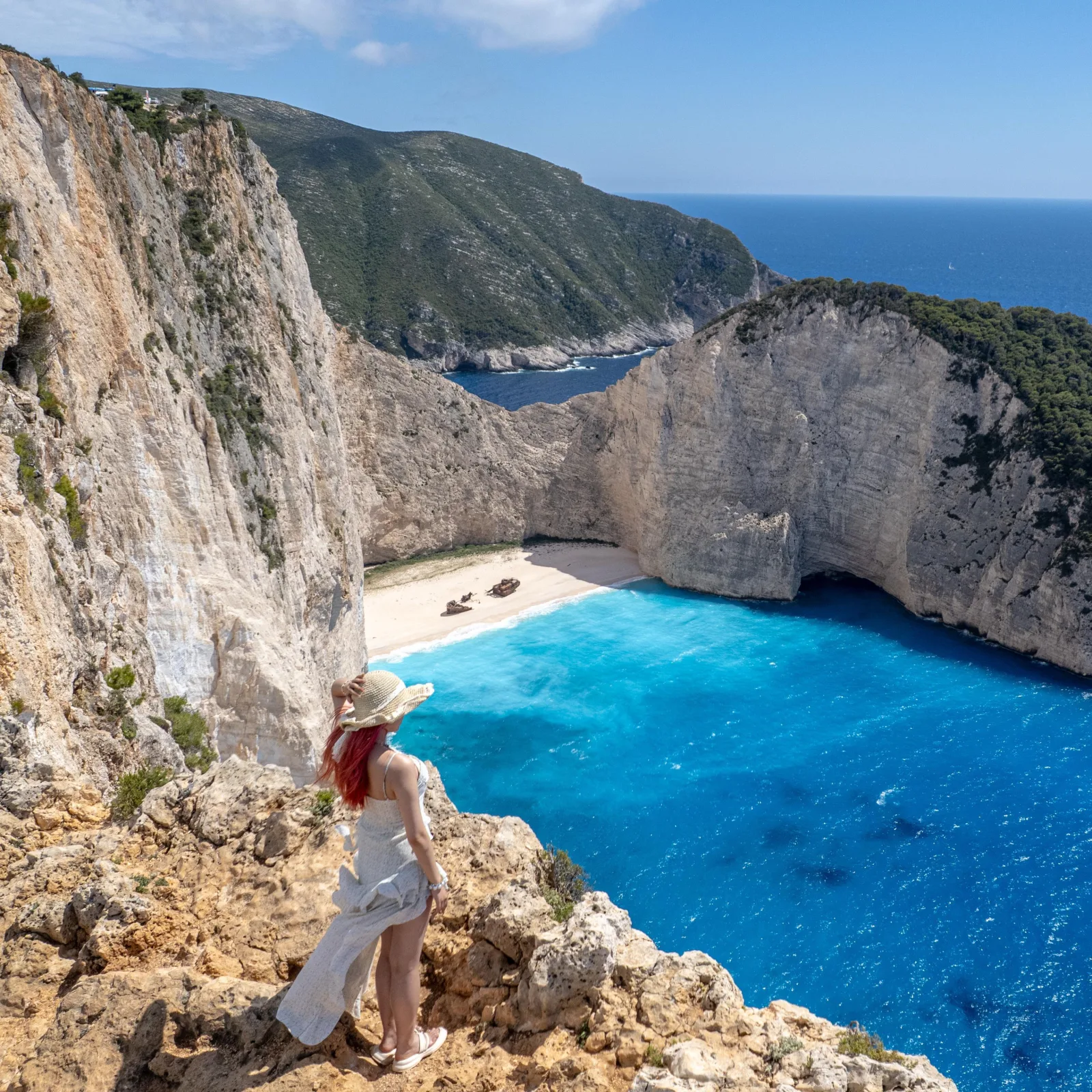 A visitor at the Navagio viewpoint above the bay, the wreck on the sand below