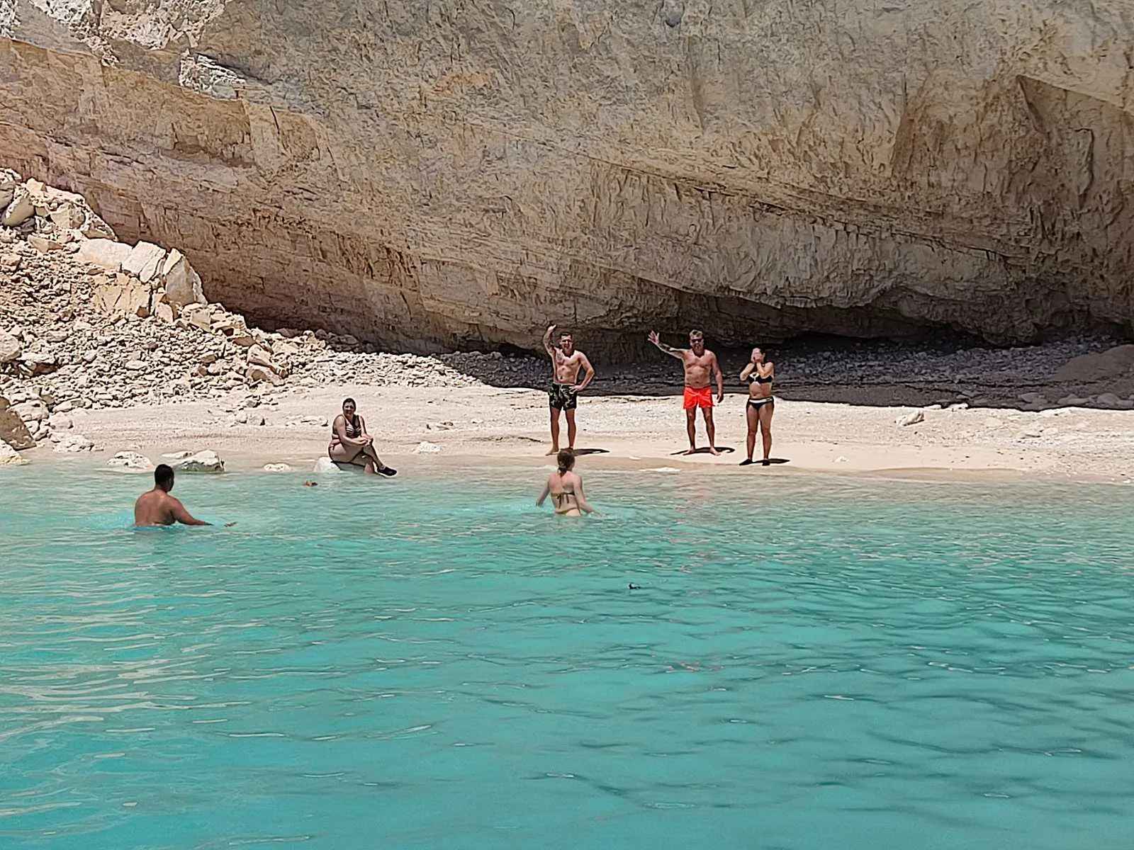 Passengers on a hidden pebble beach at the foot of the cliffs