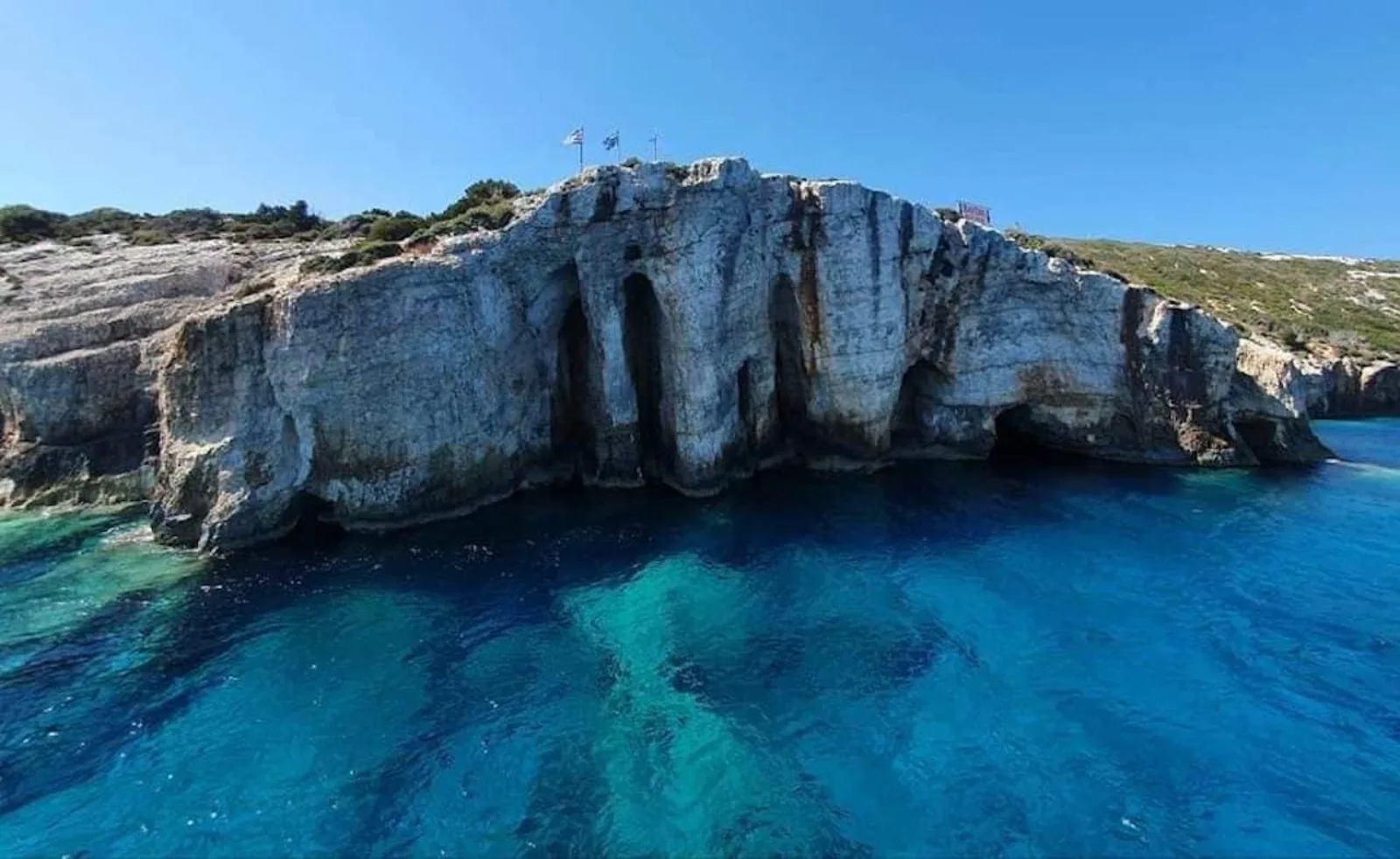 Limestone cliffs riddled with sea caves on the north coast, a small boat at one entrance