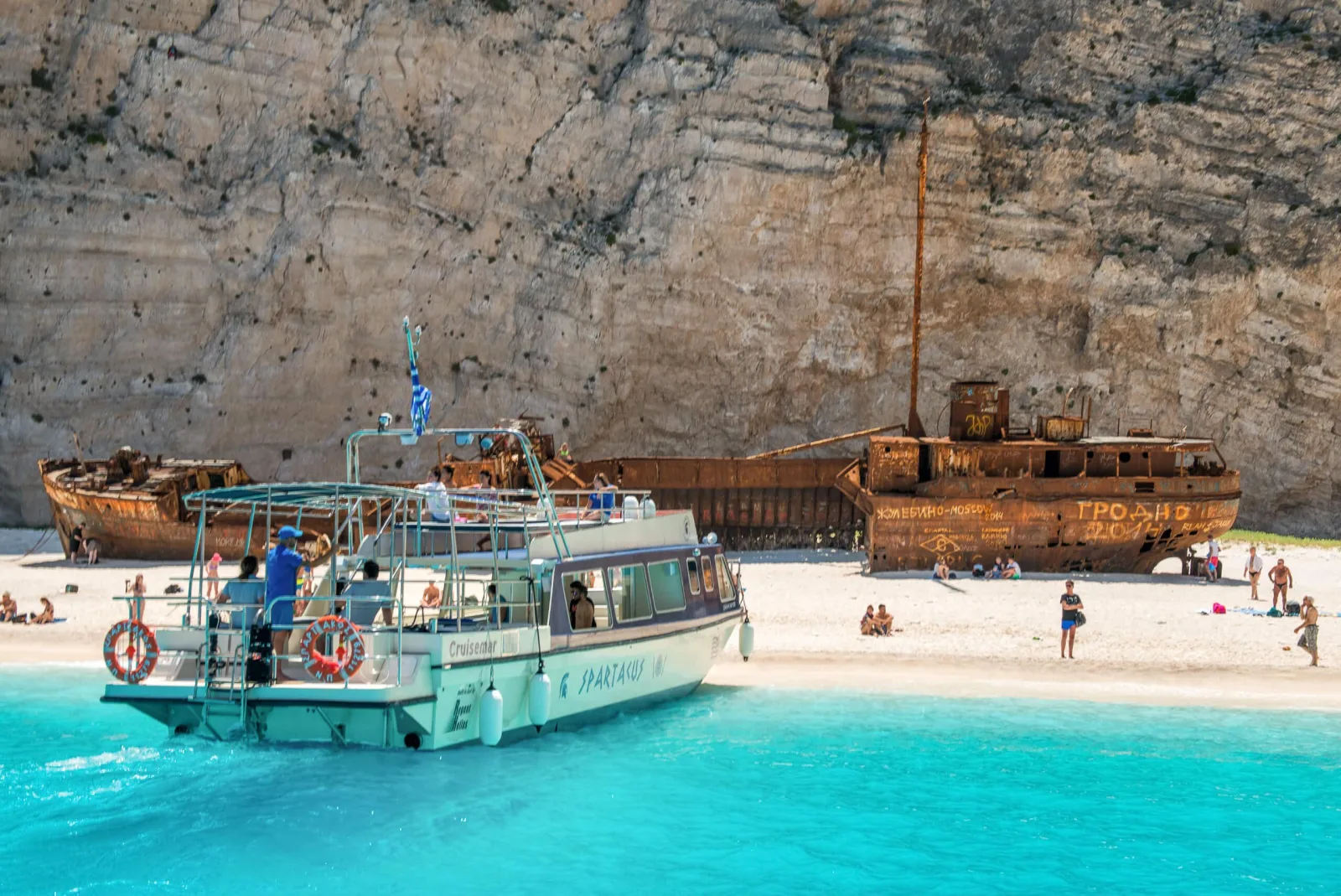 The glass-bottom boat beside the rusted Panagiotis wreck on the beach, photographed before the 2026 landing closure