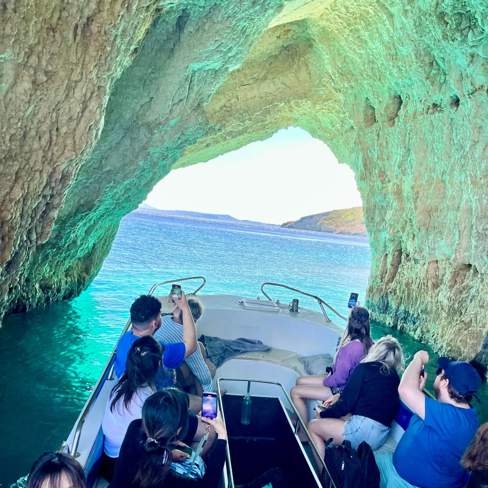 Passengers looking out from inside a sea cave arch to turquoise water