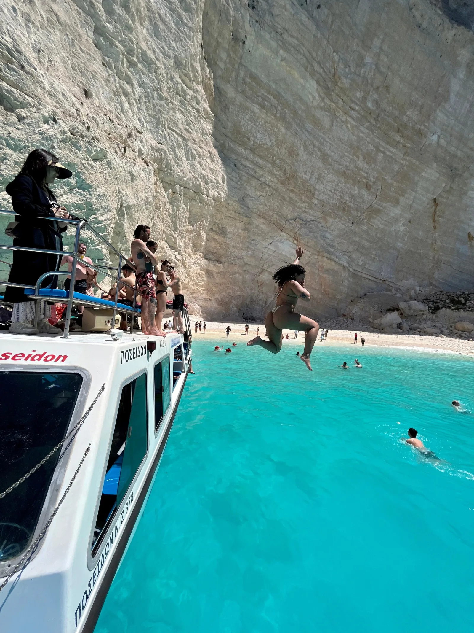Passengers jumping from the boat's upper deck into Navagio bay, photographed before the 2026 in-bay swimming closure