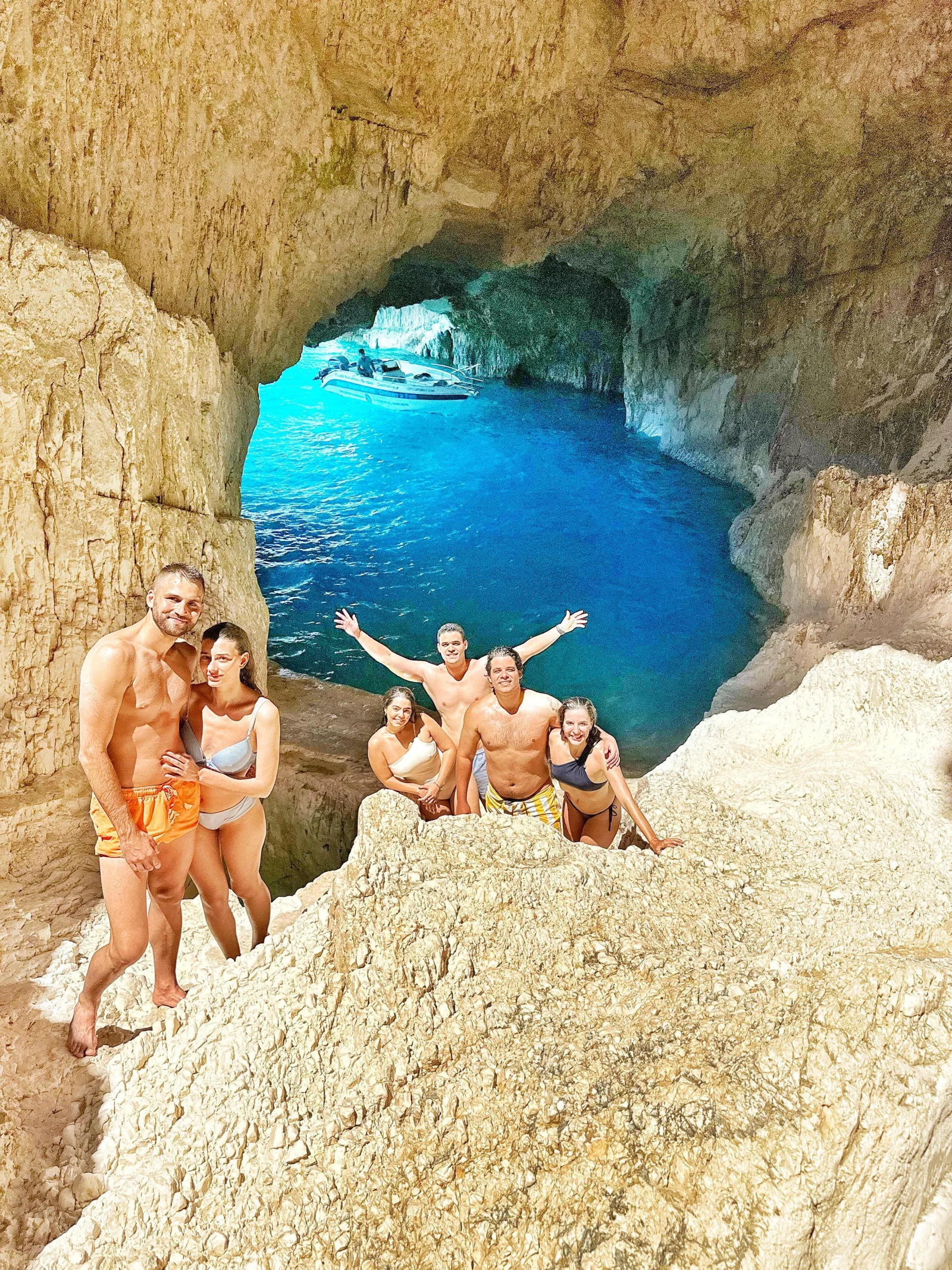 A group posing on the rocks above a blue cave pool on the west coast