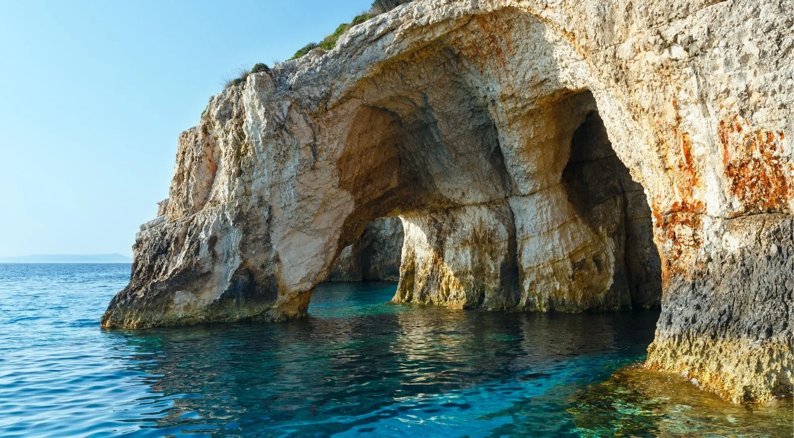 A limestone arch of the Blue Caves at Cape Skinari with turquoise water beneath