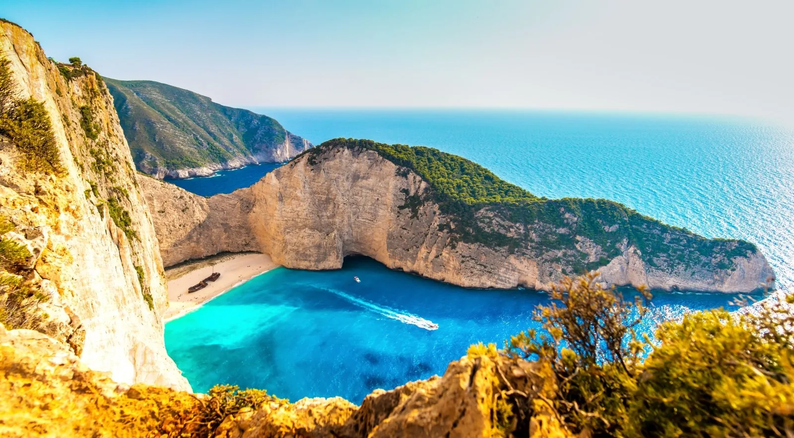 Navagio from the cliff with tour boats gathered in the turquoise bay